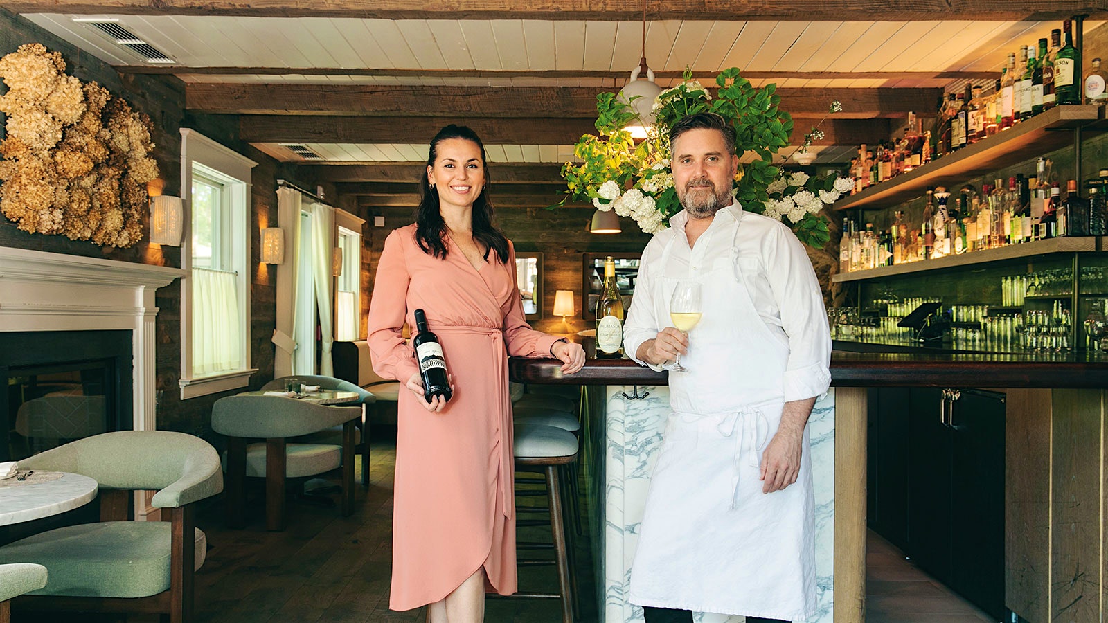 North Fork Table & Inn’s beverage director Amy Racine, who holds a wine bottle, and chef John Fraser, who holds a glass of white wine